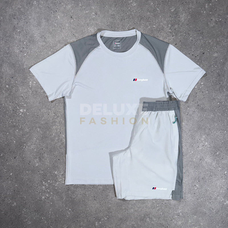 A white and gray athletic short-sleeve shirt and matching shorts laid flat on a gray concrete surface. The shirt has gray shoulder panels and a small chest logo, while the shorts have gray side panels and an elastic waistband.